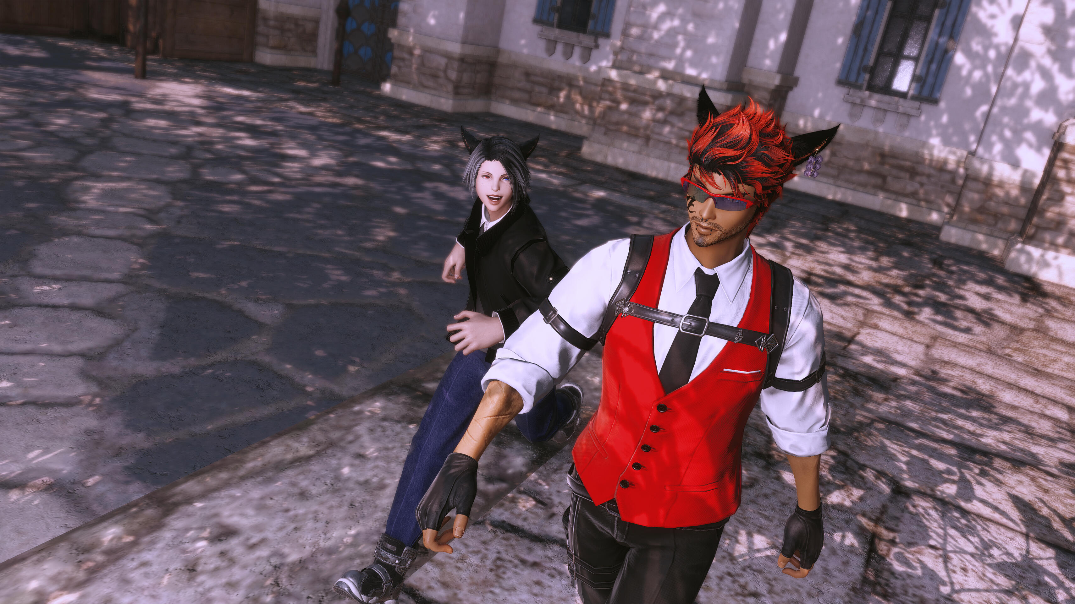 Maxx and Kell walk the streets of Valnain. In the foreground, Maxx—with spiky red hair, a red vest, and a futuristic visor—walks forward purposefully. Behind him and slightly to the left, Kell—with black hair and a black jacket—follows smiling. They are on a stone-paved street.